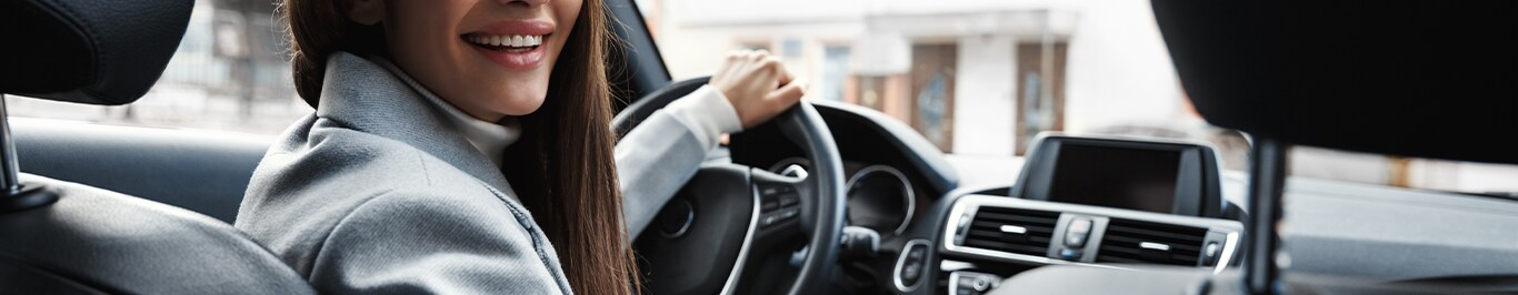 Enjoy A Test Drive At Bobby Rahal Acura in Mechanicsburg, PA | Back seat view of a woman driving her car while looking back and smiling