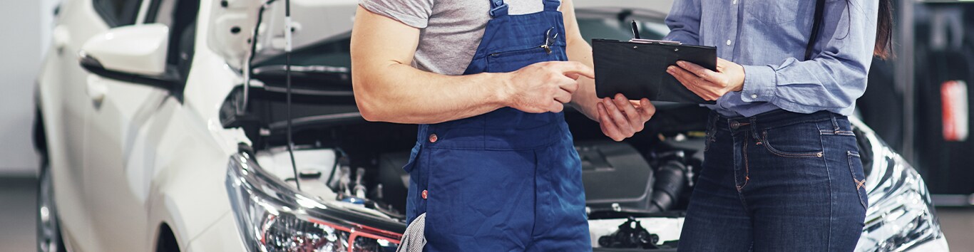 Learn Maintenance Warning Signs at Bobby Rahal Acura in Mechanicsburg, PA | Mechanic and customer holding a clip board and discussing about the white car behind them