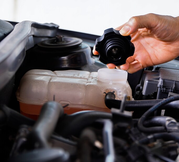 How to Get Your Car Summer Ready at Bobby Rahal Acura in Mechanicsburg, PA | Hand holding lid to a radiator reservoir to check coolant levels