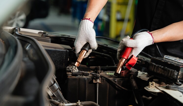Everything You Need to Know about Your Car Battery at Bobby Rahal Acura | Person with white gloves connecting battery cables to a battery in the engine bay