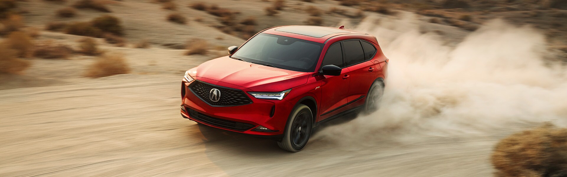 Accessories that help keep your Acura protected at Bobby Rahal Acura in Mechanicsburg, PA | Red 2022 Acura MDX Driving Fast Through Dusty Desert at Sunset