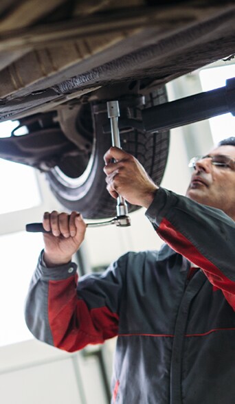 Vehicle Warranty Information at Bobby Rahal Acura in Mechanicsburg, PA | Mechanic working underneath a car with a long ratchet tool