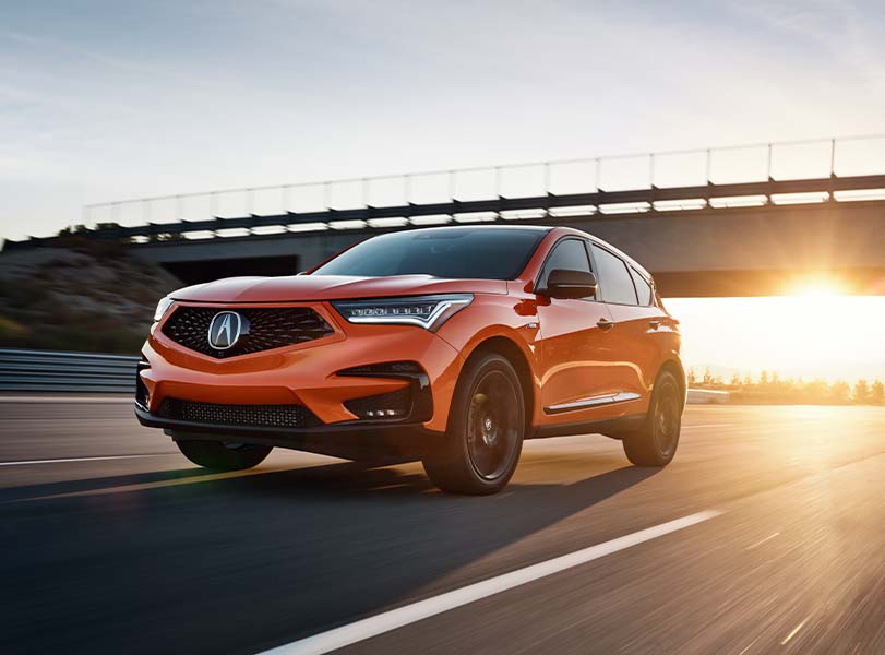 Model Features of the 2021 Acura RDX at Bobby Rahal Acura | Profile View of Orange 2021 Acura RDX Driving Under Underpass