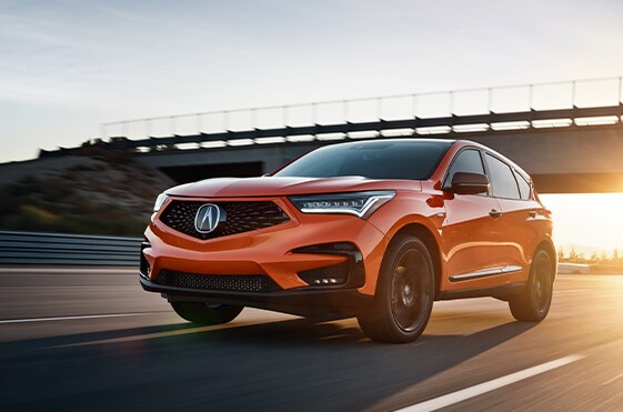 Compare the 2021 Acura RDX vs. the 2021 Mercedes Benz GLC Class at Bobby Rahal Acura | RDX driving on highway with sunset
