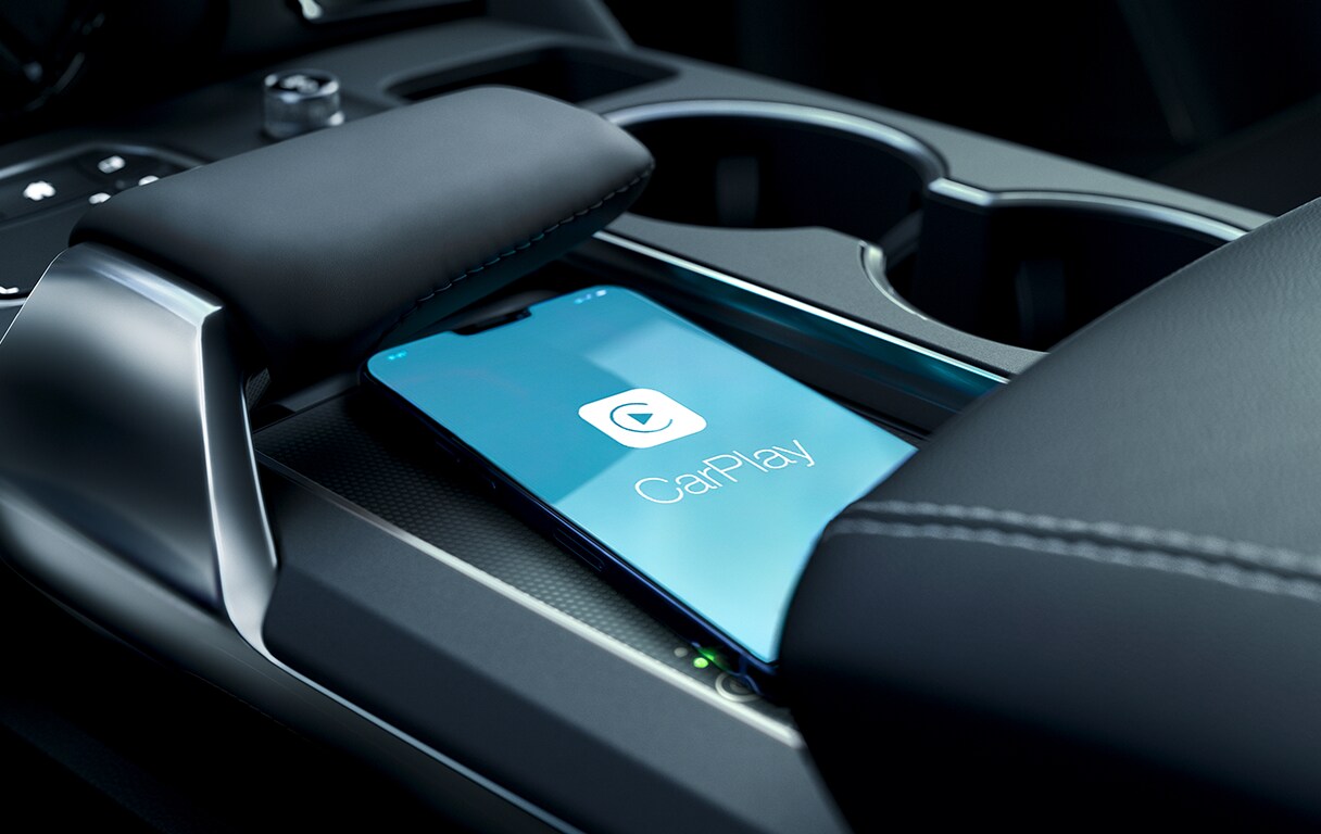 Android Auto vs. Apple CarPlay at Bobby Rahal Acura in Mechanicsburg, PA | Apple Carplay shown on cellphone screen while charging on wireless charger near car shifter