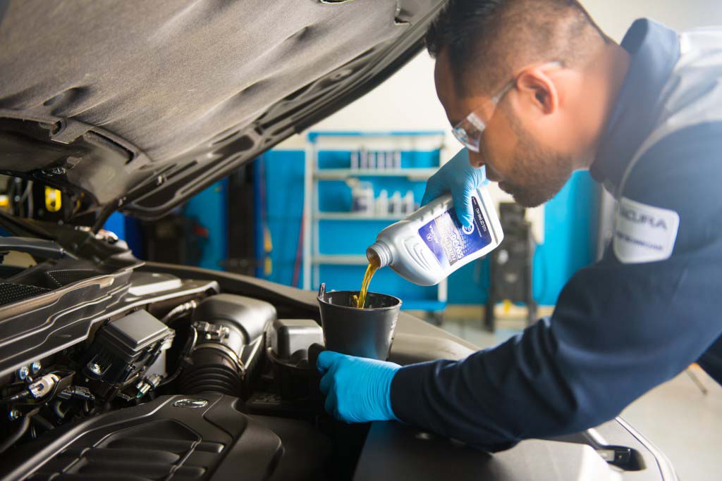 Basic Car Maintenance and Servicing Checklist | Bobby Rahal Acura | Acura service technician filling engine oil in acura vehicle