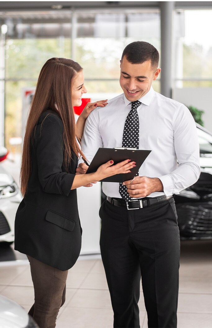Lexus Dealer in Lancaster, PA | Woman showing man in white shirt a clipboard of car deals inside of a dealership