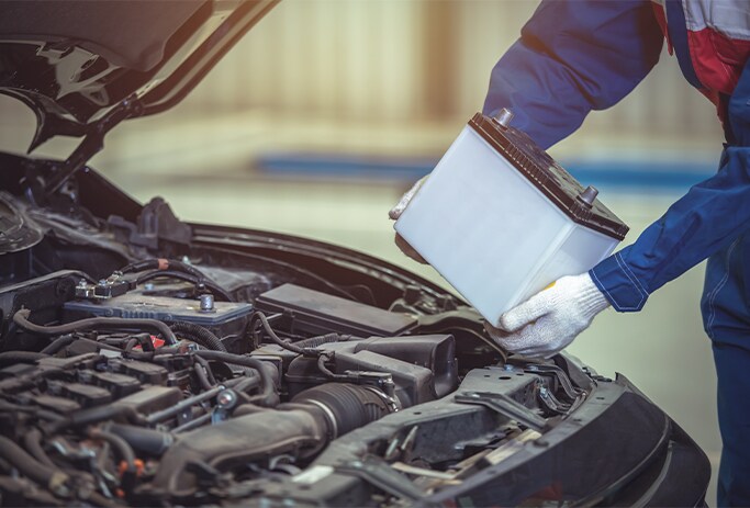 How to Get Your Car Summer Ready at Bobby Rahal Toyota in Mechanicsburg, PA | Mechanic putting in new battery into a car while wearing grey gloves