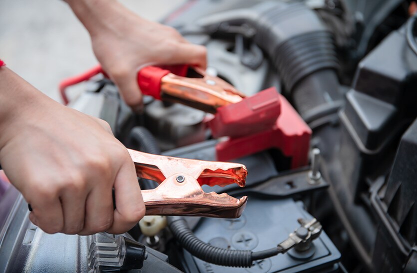 Everything You Need to Know about Your Car Battery at Bobby Rahal Toyota | A person holding on to battery cables about to connect it to car battery