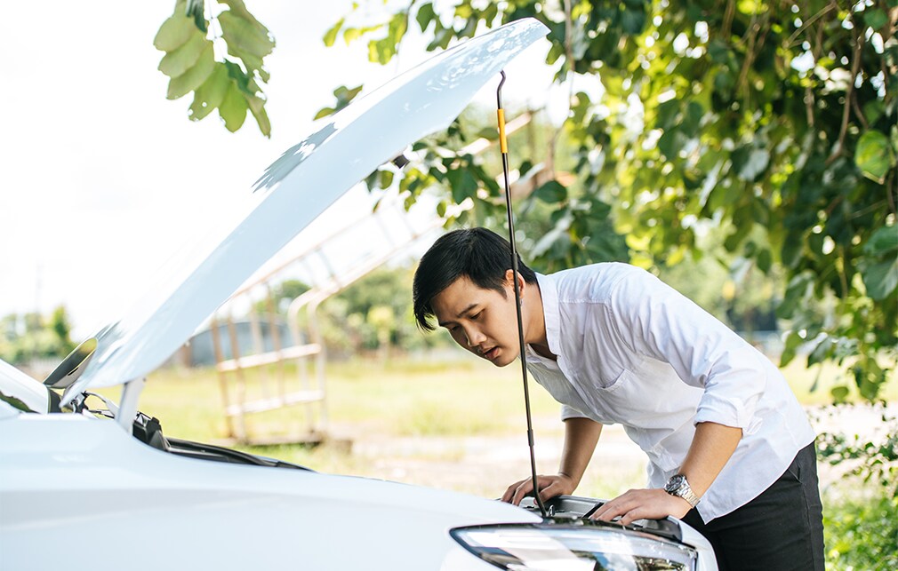 Learn Maintenance Warning Signs at Bobby Rahal Toyota in Mechanicsburg, PA | Man in white shirt looking under the hood of his white car