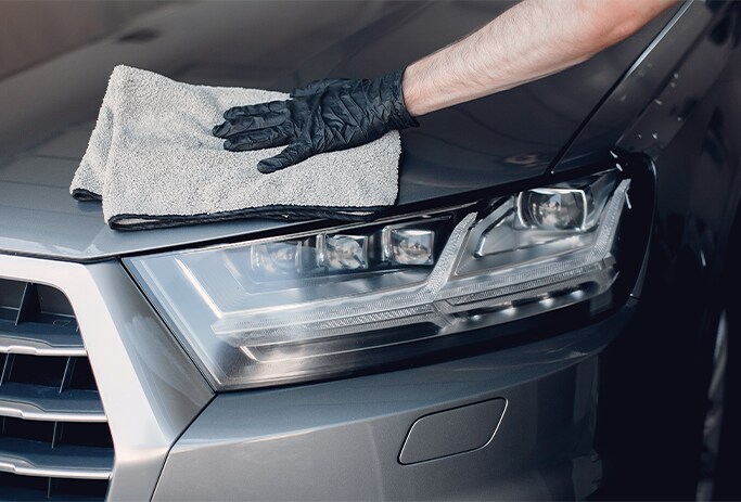How to Get Your Car Summer Ready at Bobby Rahal Toyota in Mechanicsburg, PA | Person with black gloves wiping down his grey car with white rag