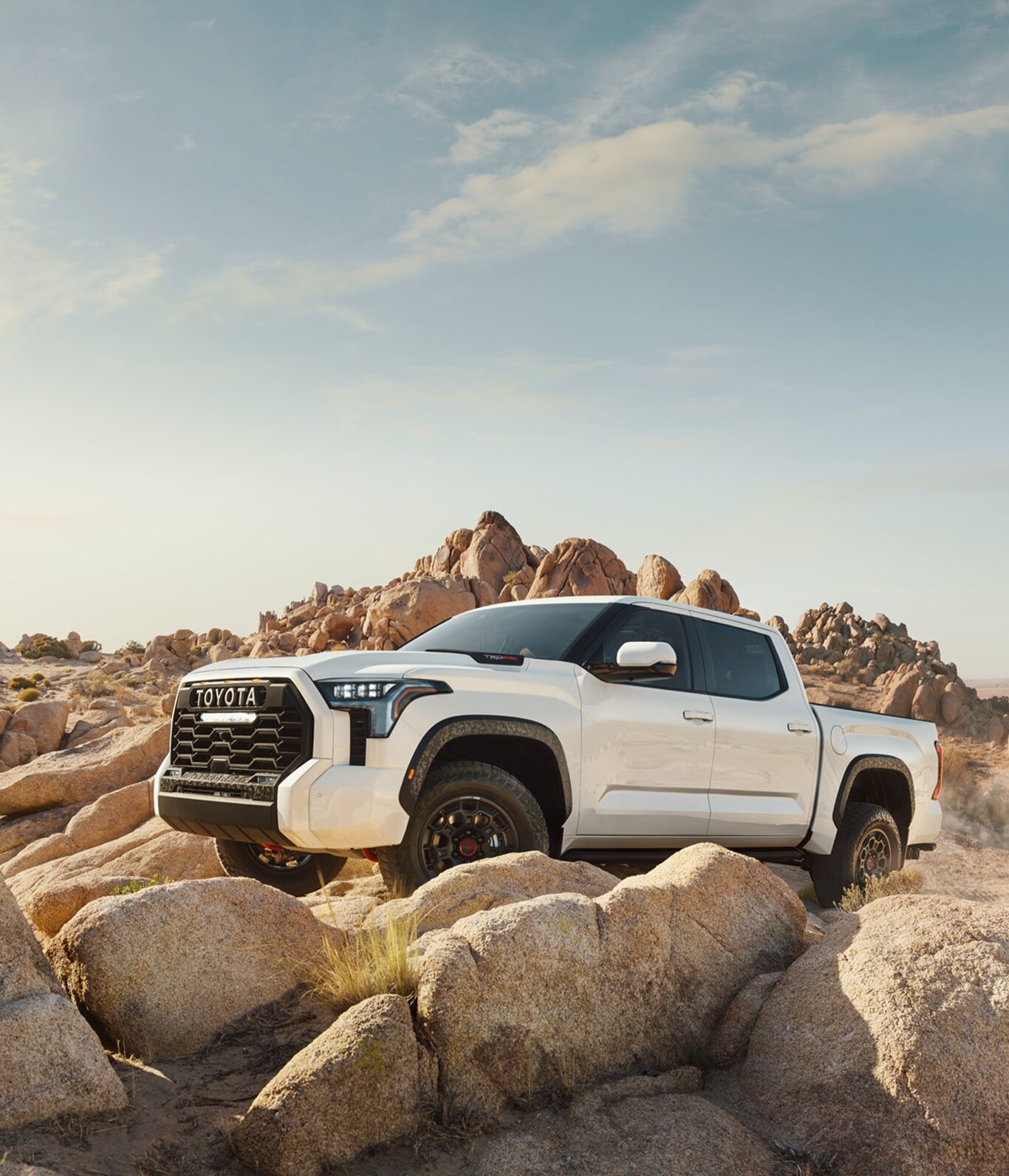 2023 Toyota Tundra vs. 2023 Ford F-150 at Bobby Rahal Toyota | White 2023 Toyota Tundra parked on a hill filled with giant rocks