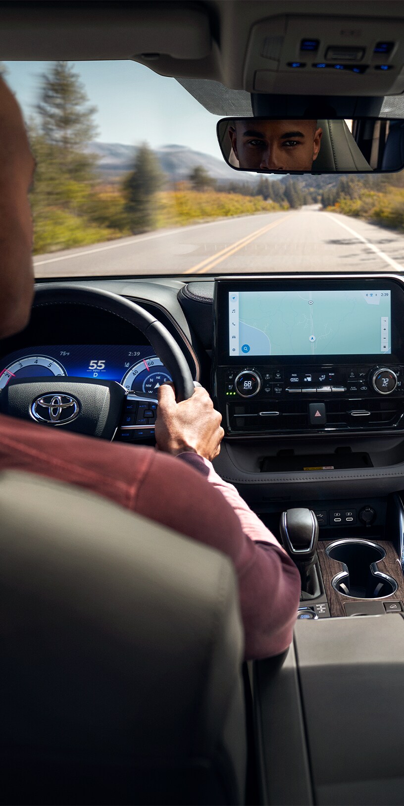 2023 Toyota Highlander at Bobby Rahal Toyota in Mechanicsburg, PA | Man in dark red shirt is sitting in the drivers seat and driving his 2023 Toyota Highlander during the day