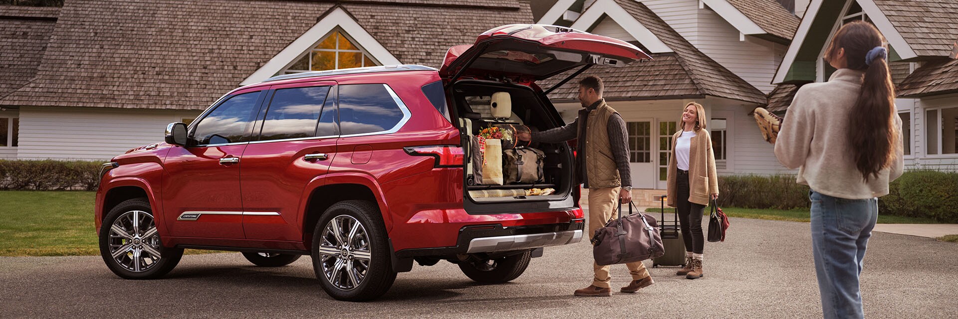 Model Features of the All-New 2023 Toyota Sequoia at Bobby Rahal Toyota | Family Loading Red 2023 Toyota Sequoia with Luggage in Front of Home