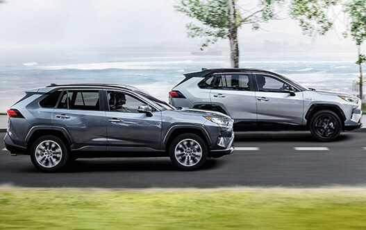 Model Features of the 2021 Toyota RAV4 at Bobby Rahal Toyota | Two RAV4's driving fast past ocean