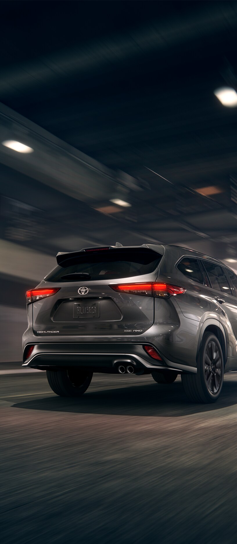 2023 Toyota Highlander at Bobby Rahal Toyota in Mechanicsburg, PA | Rear view of a grey 2023 Toyota Highlander driving down the road