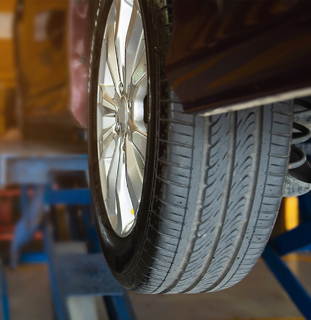 Learn Maintenance Warning Signs at Bobby Rahal Toyota in Mechanicsburg, PA | Shot of a used/worn out tire on a black car while on the lift