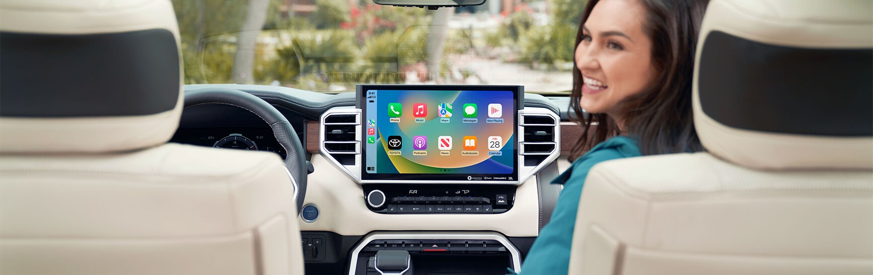 Android Auto vs. Apple CarPlay at Bobby Rahal Toyota in Mechanicsburg, PA | Woman looking back while sitting in the passenger seat with Apple Carplay displayed on screen