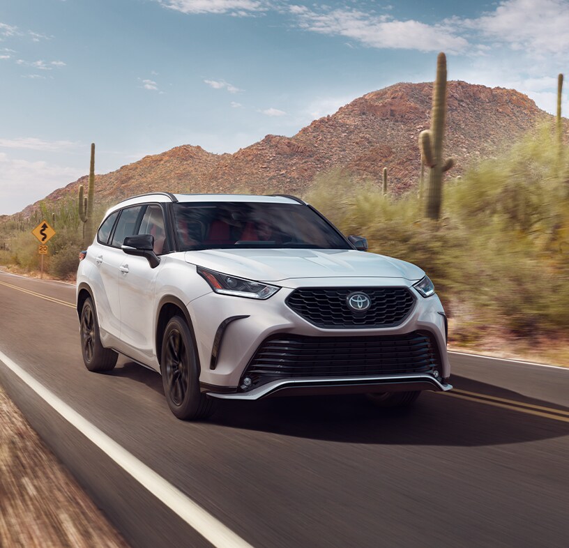 2023 Toyota Highlander at Bobby Rahal Toyota in Mechanicsburg, PA | White 2023 Toyota Highlander driving down a dessert road during the day