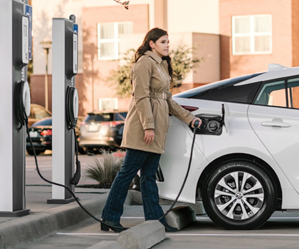 How to prepare your home for your new Plug-in Hybrid Vehicle at Bobby Rahal Toyota in Mechanicsburg, PA | Woman Plugging in Her 2021 Toyota Prius Prime Outside of Condos