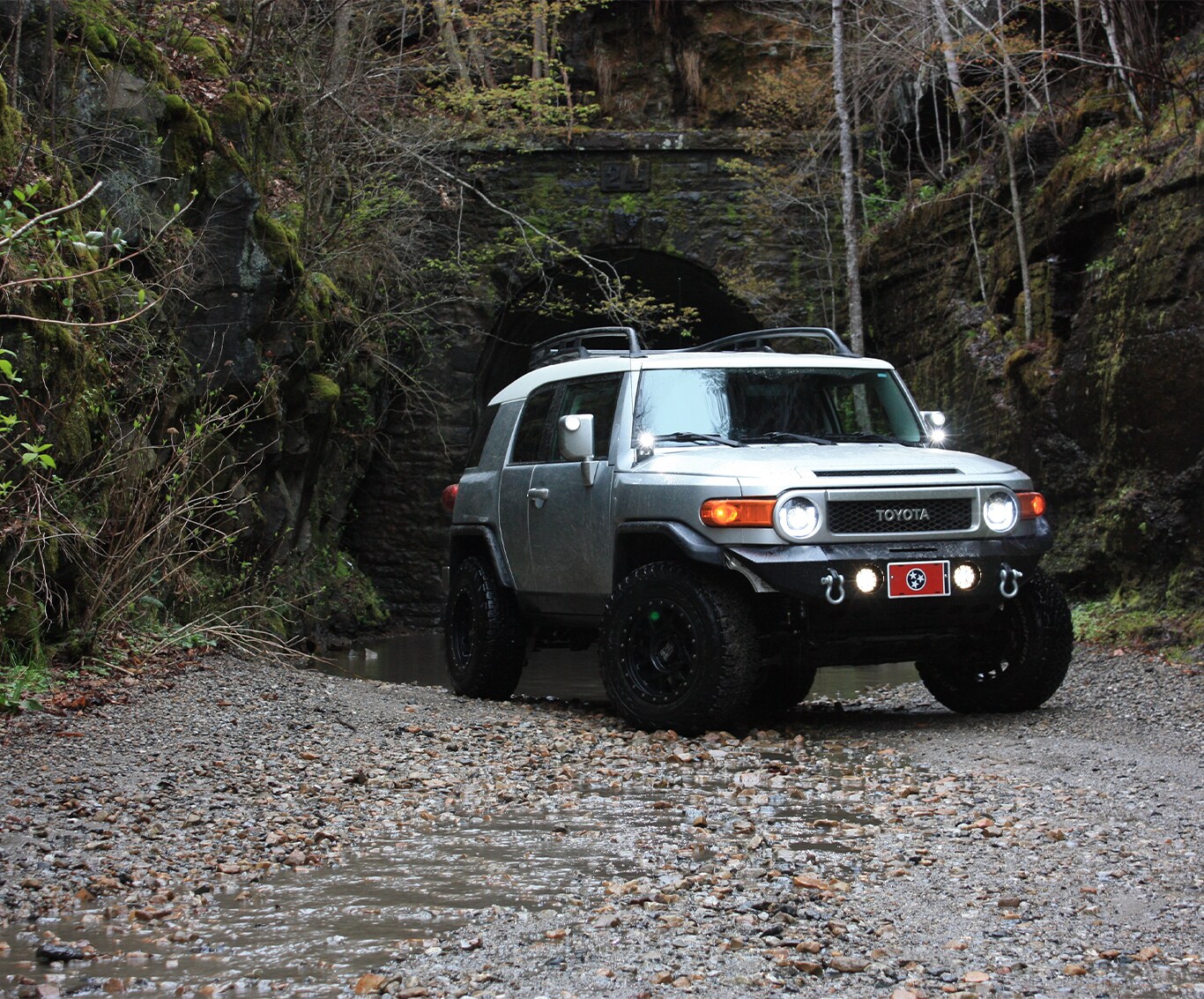 What is Tire and Rim Protection? | Bobby Rahal Toyota | Silver Toyota FJ Cruiser parked on a dirt road with a forest behind it on a cloudy day