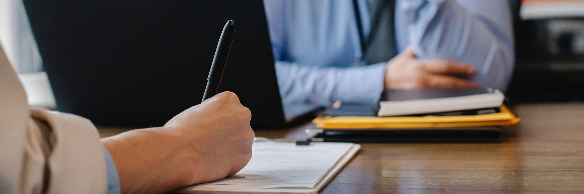 Leasing versus Buying a Toyota at Bobby Rahal Toyota in Mechanicsburg, PA | Close Up of One Person Signing Contract at Desk on the Left while Sales Representative Sits Across from Them on the Right