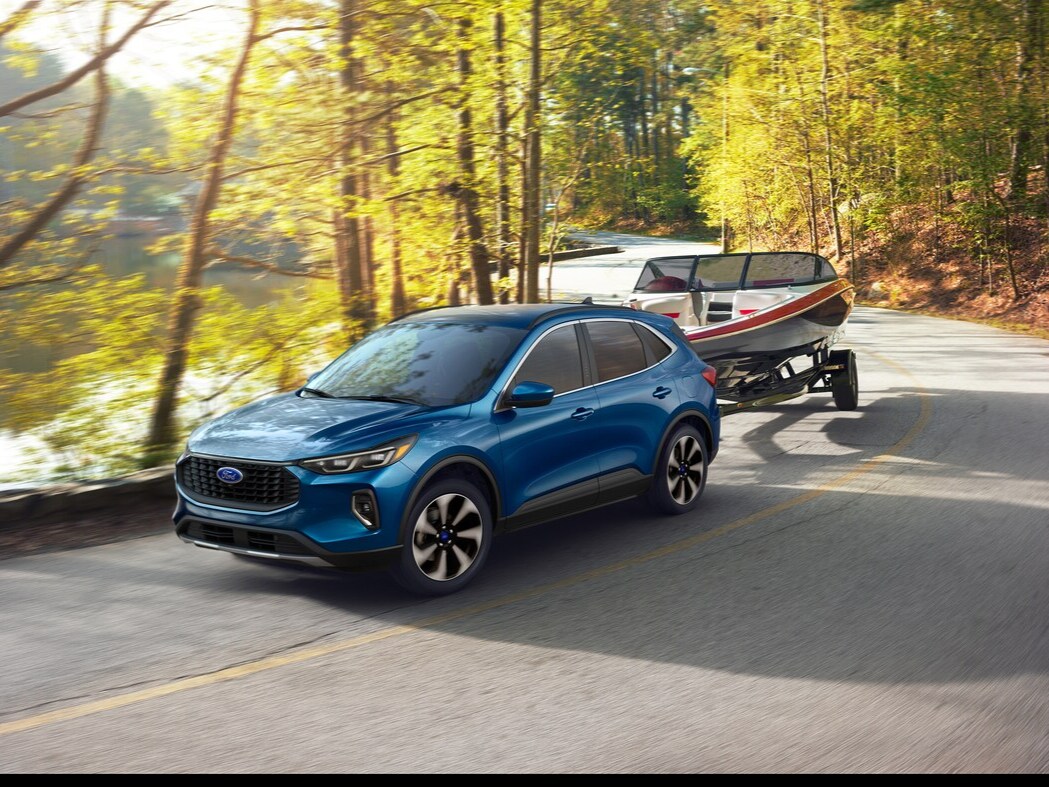Blue Ford Escape Towing Boat Blue Ford Escape towing a boat on a sunny day