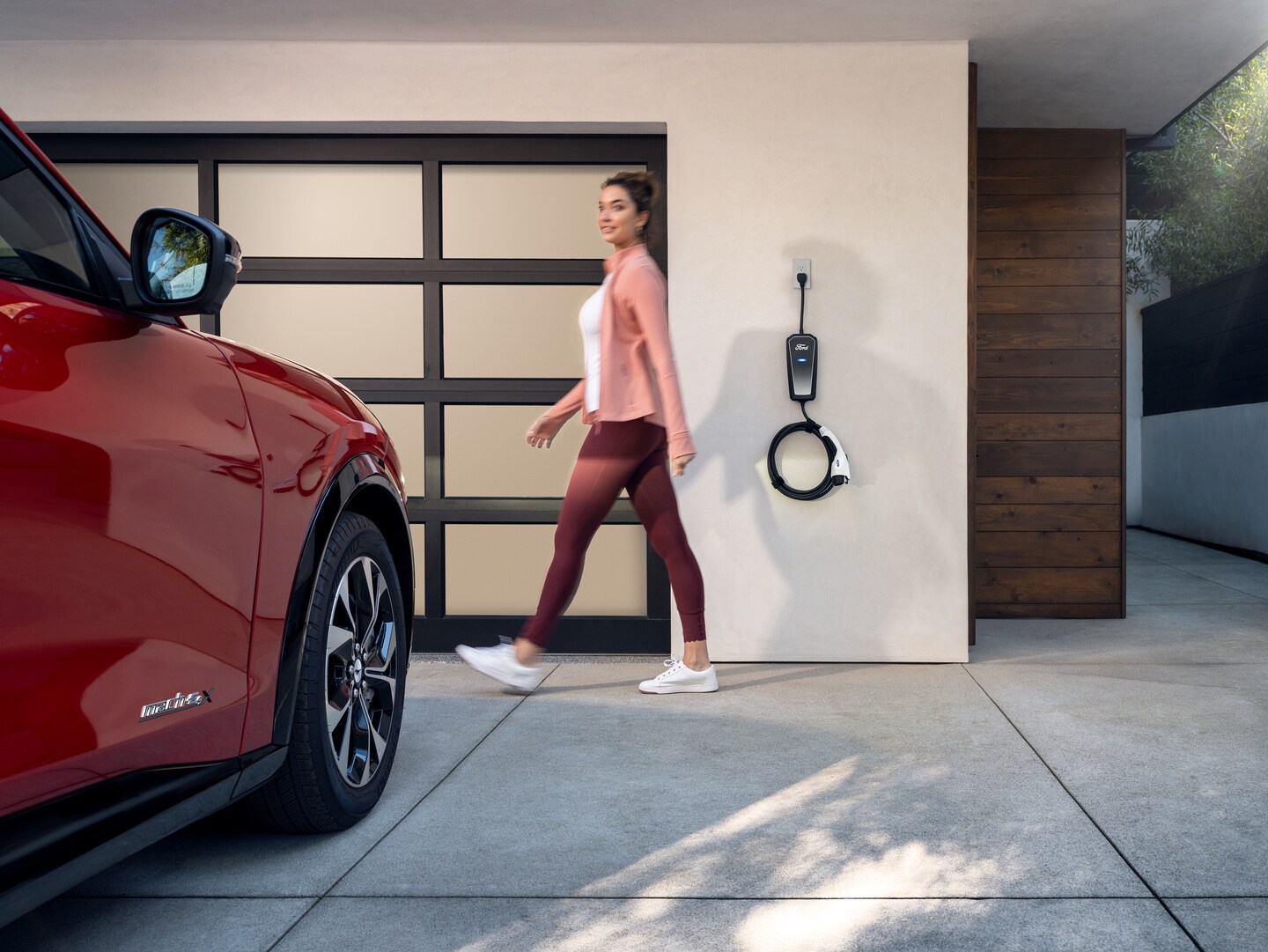 Red Ford electric vehicle charging in driveway with portable adaptor