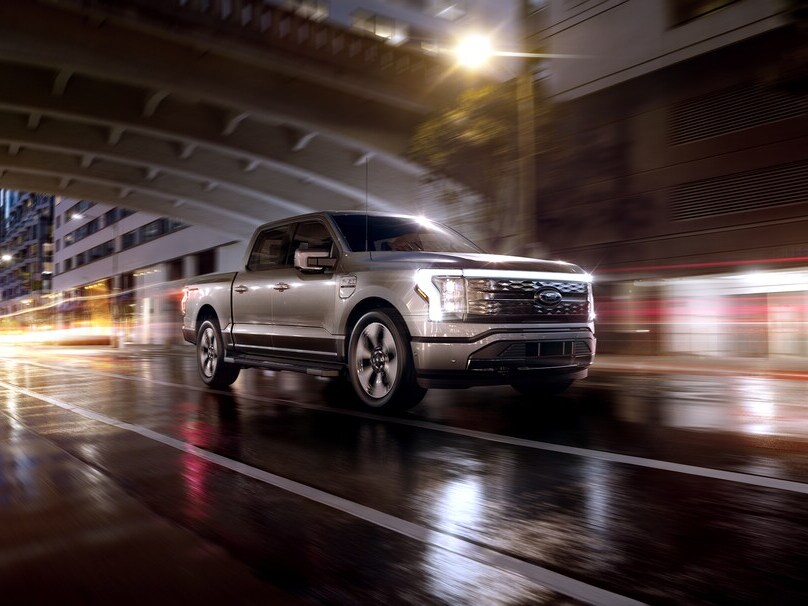 Silver Ford F-150 Lightning driving on city road at night
