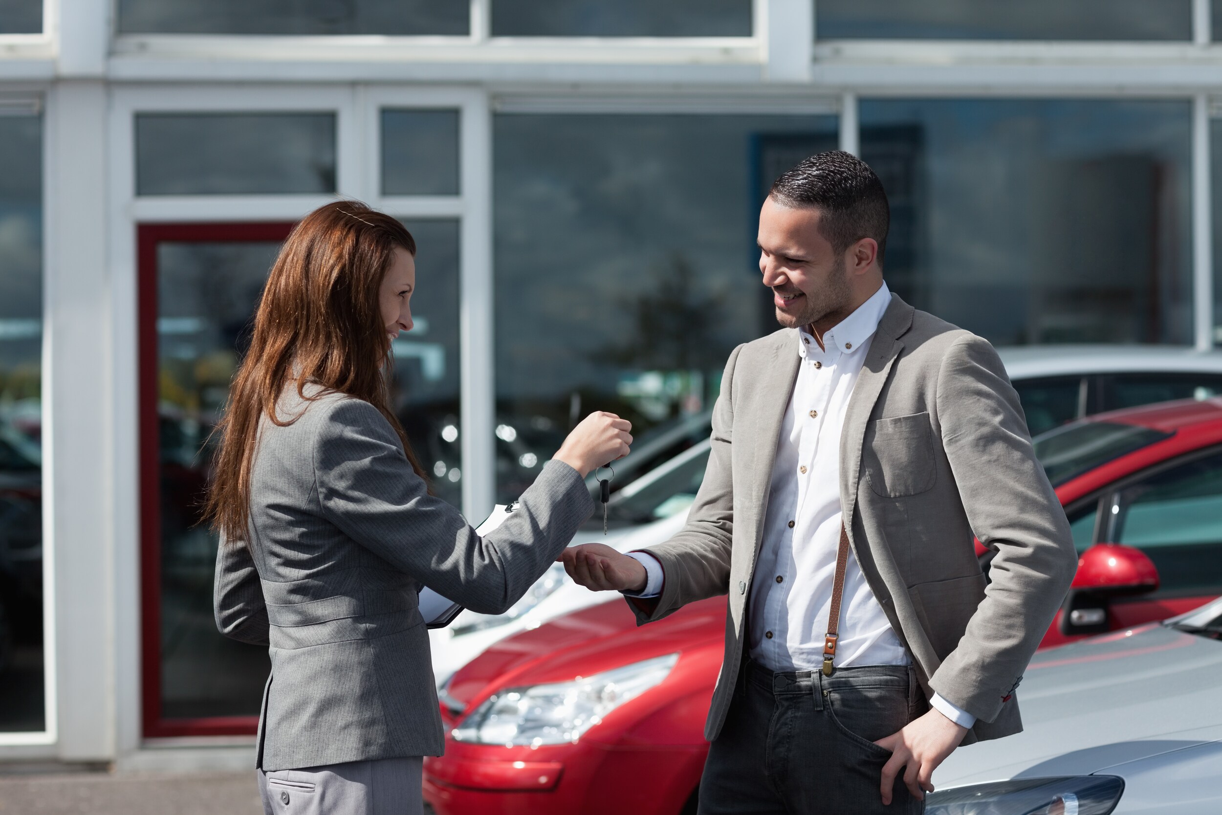 why-buy-used-bob-penkhus.jpg a car sales lady meeting with a business man outside a dealership viewing used cars