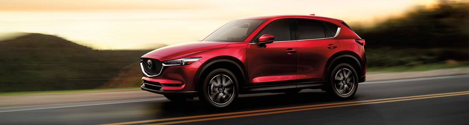 2018 Mazda CX-5 used SUVs in Colorado Springs Bob Penkhus Dealerships.png Driver side view of a used 2018 Mazda CX-5 SUV driving down an open road with blurred street lines