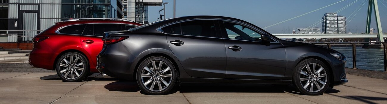 2019 Mazda6 Configurations Colorado Springs Bob Penkhus Mazda Motor City.png A 2019 Mazda6 Sport trim parked in front of a 2018 Mazda6 wagon by a dock on a bay of water