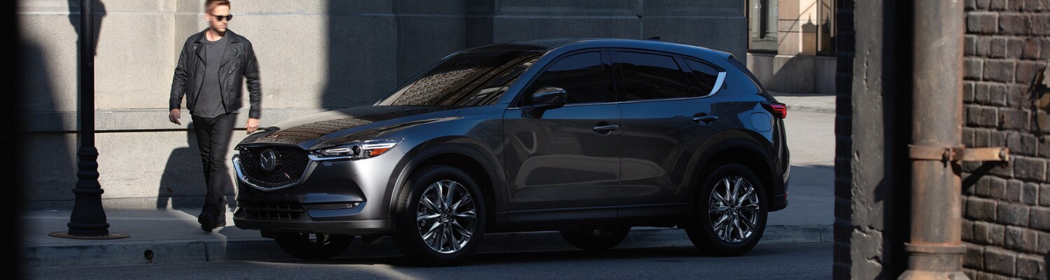 2019 Mazda CX-5 in Colorado Springs Bob Penkhus Mazda Motor City.png A 2019 Mazda CX-5 parked on an empty city street as the driver walks around the SUV to get in