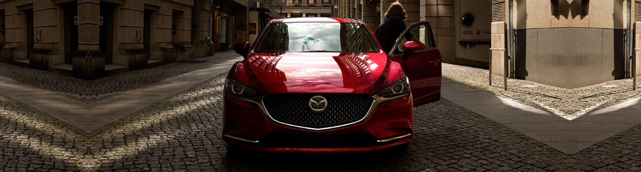 2019 Mazda6 sedan in Colorado Springs at Bob Penkhus Mazda Powers.png Front exterior view of a red 2019 Mazda6 sedan parked on a cobblestone road by government buildings