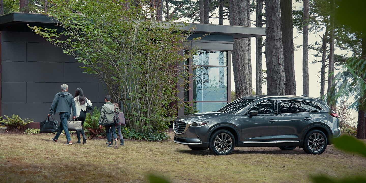 2020-mazda-cx-9-bob-penkhus-mazda-dealership-colorado-springs.jpg A 2020 Mazda CX-9 parked while a family walks into a modern cabin in the woods
