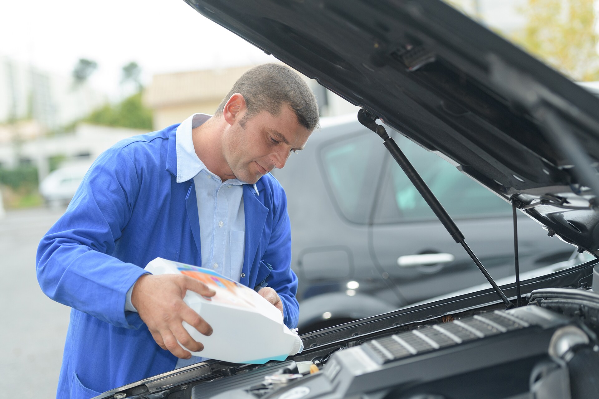 How to prepare your vehicle for the winter season | Man filling up anti-freeze in car