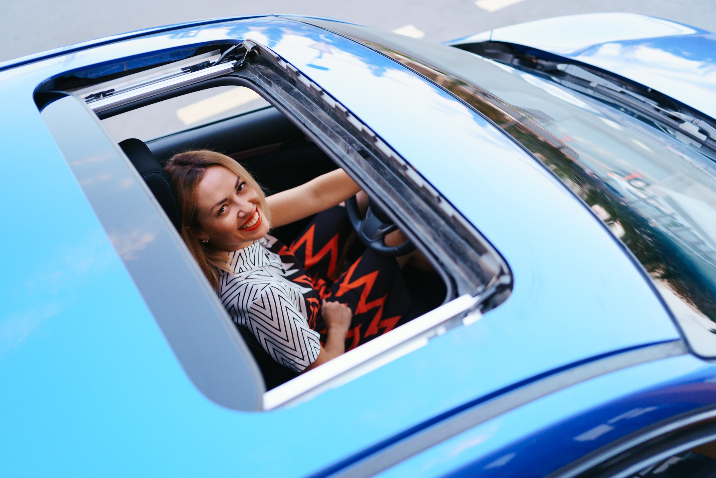 BWhat you can get to personalize your vehicle at Boch Honda, Boch Toyota, Boch Nissan, Boch Hyundai, Boch Chevrolet, Genesis of Norwood, Boch Toyota South, Boch Honda West, Boch Nissan South, & Boch New to You in Massachusetts | Young woman looking up at camera through sun roof of blue car