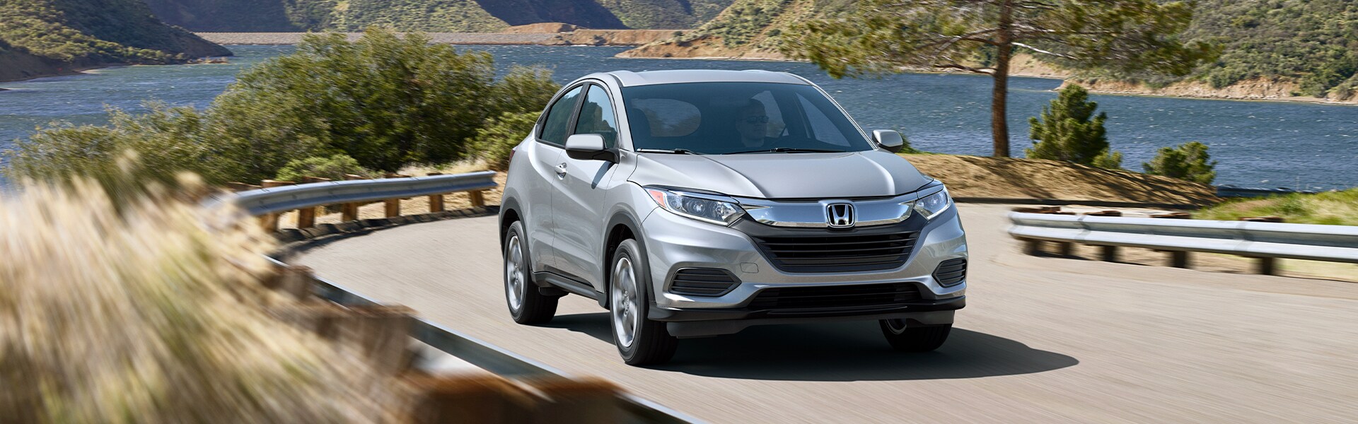 Boch Honda West is a Family Owned Dealership near Acton, MA | Silver 2020 HR-V Driving Around Bend in Front of Lake Boch Honda West is a Family Owned Dealership near Acton, MA | Silver 2020 HR-V Driving Around Bend in Front of Lake
