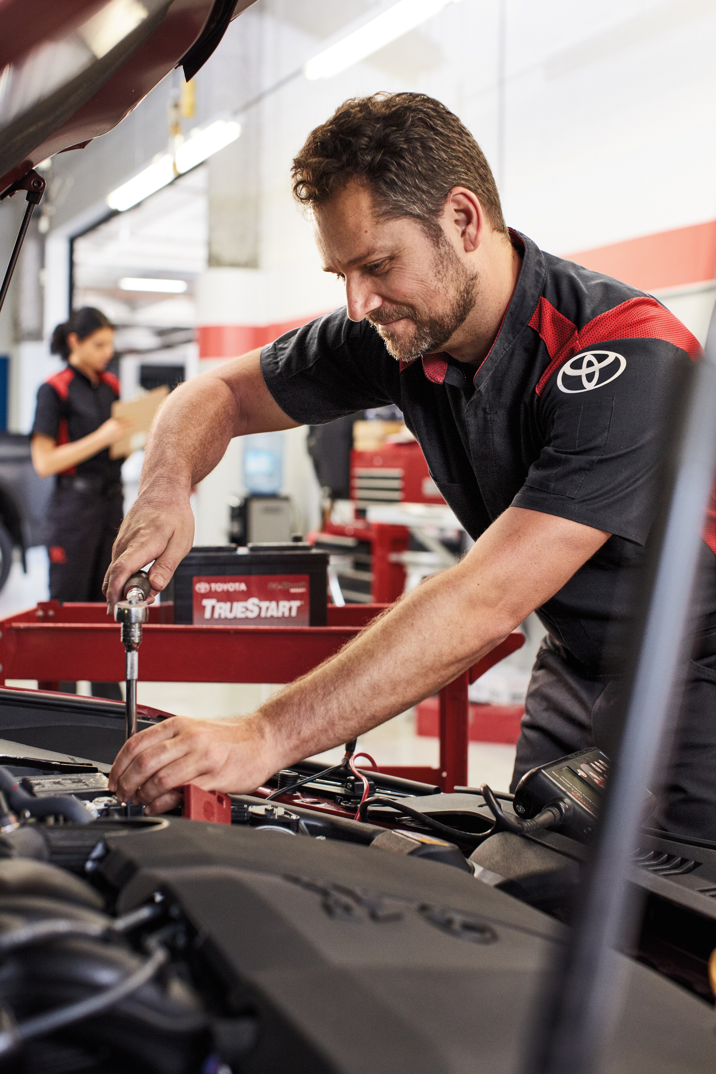 Boch Toyota is a Family Owned Dealership near Boston, MA | Toyota mechanic replacing battery in vehicle