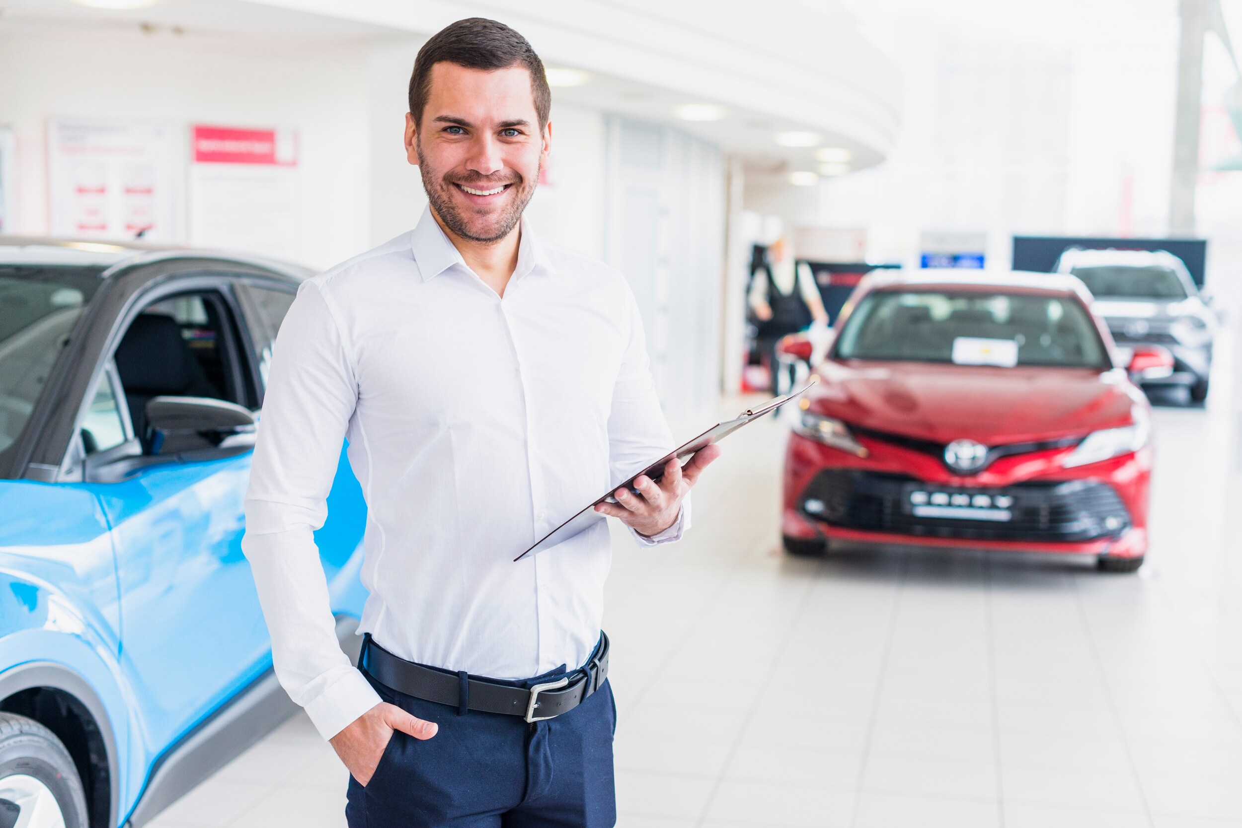 Boch Toyota is a Family Owned Dealership near Boston, MA | Toyota car salesman standing in dealer showroom holding clipboard