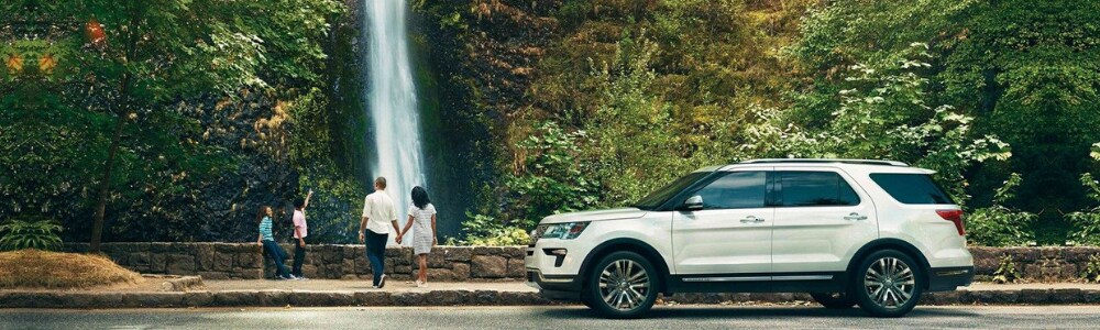 2019 Ford Explorer SUV near Seattle at Bowen Scarff Ford in Kent WA.png Driver side angle of a white 2019 Ford Explorer parked on the side of the road by a waterfall as the family gets out to enjoy the view
