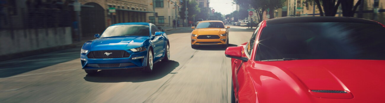 2019 Ford Mustang configurations Bowen Scarff Ford near Seattle.png Front view of three 2019 Ford Mustangs driving down a city street where one is blue, one is red and one is yellow
