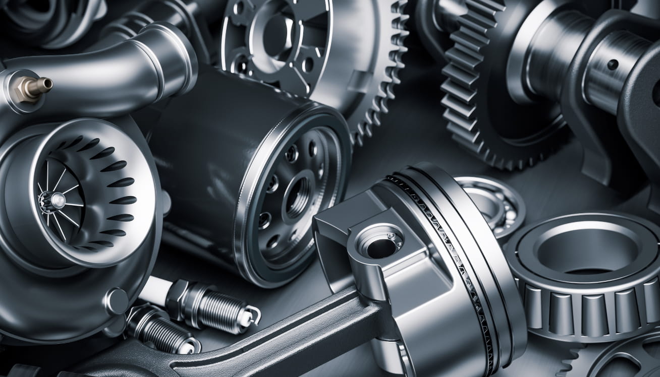 Assortment of automotive engine components, including gears, pistons, bearings, and spark plugs.