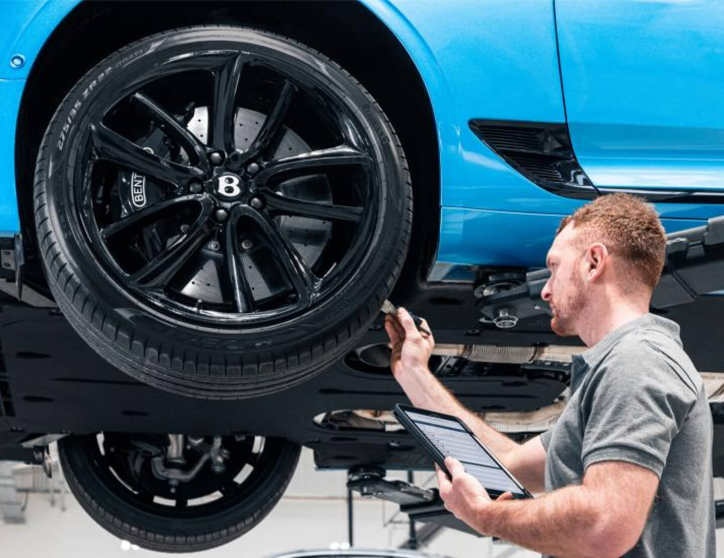Bentley Continental on a service lift during a multi-point tire inspection.