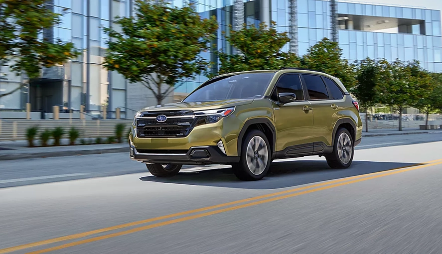Green 2026 Subaru Forester Hybrid driving on a city street, front three-quarter view