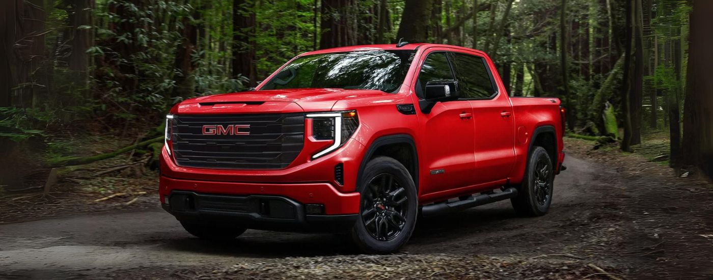 Red 2024 GMC Sierra 1500 Evelation parked in a forest after visiting a GMC dealer in Miami.