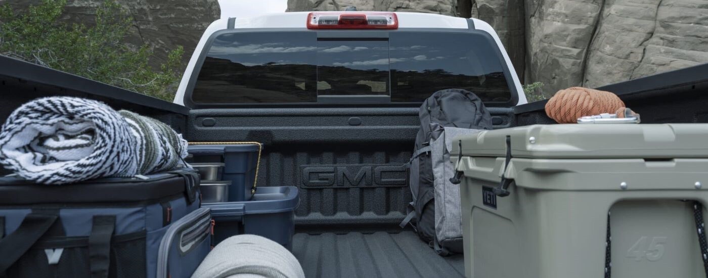 Gear loaded into the bed of a white 2023 GMC Canyon AT4.