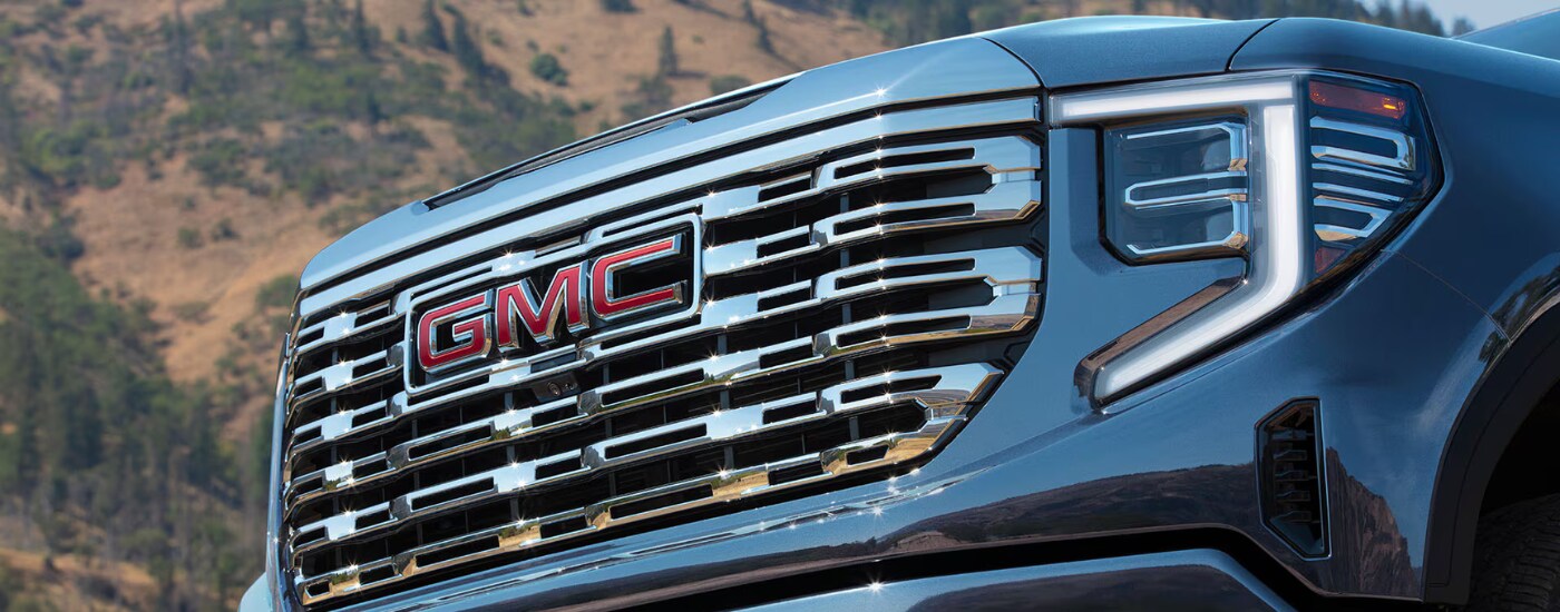 2026%20GMC%20Sierra%201500%20-%20chrome.png Chrome grille of a blue 2026 GMC Sierra 1500 Denali