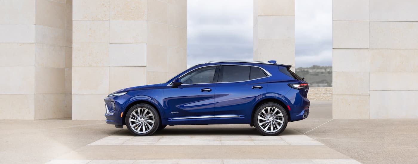 Side of a blue 2026 Buick Envison parked by a set of columns.