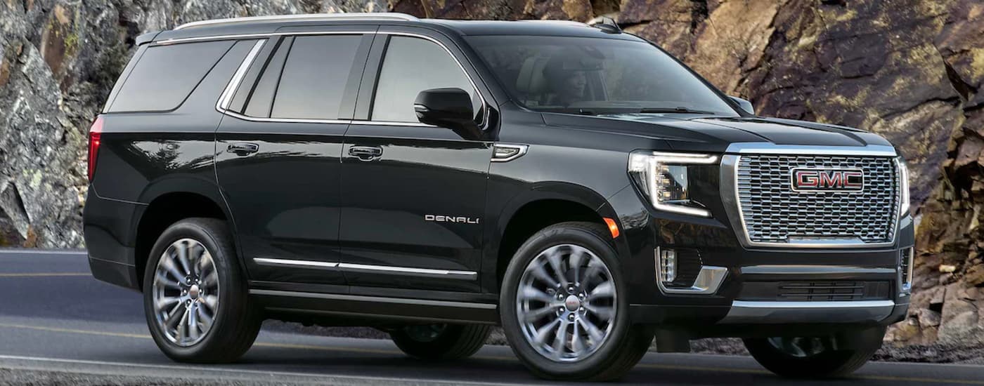 A black 2023 GMC Yukon Denali driving around a corner in a canyon Black 2023 GMC Yukon Denali driving to a GMC dealer near Doral